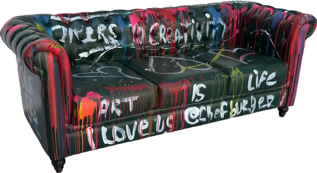 A black tufted sofa painted with colorful drips and the words Art is life and I love us