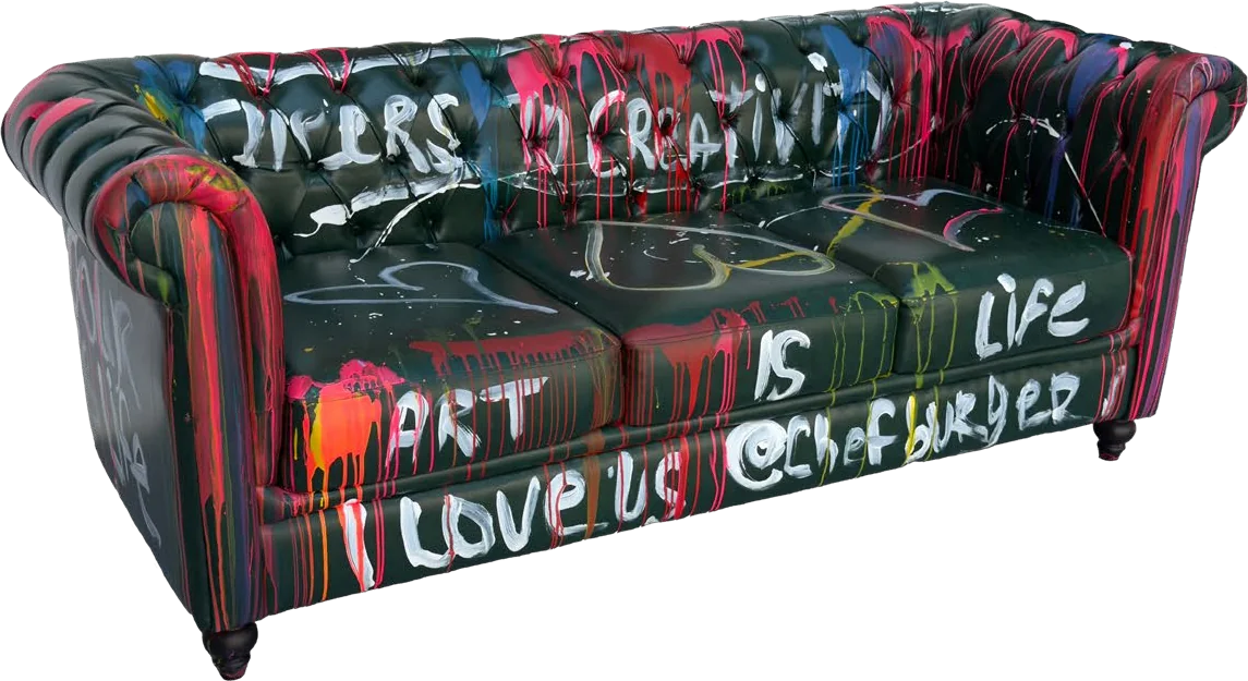 A black tufted sofa painted with colorful drips and the words Art is life and I love us